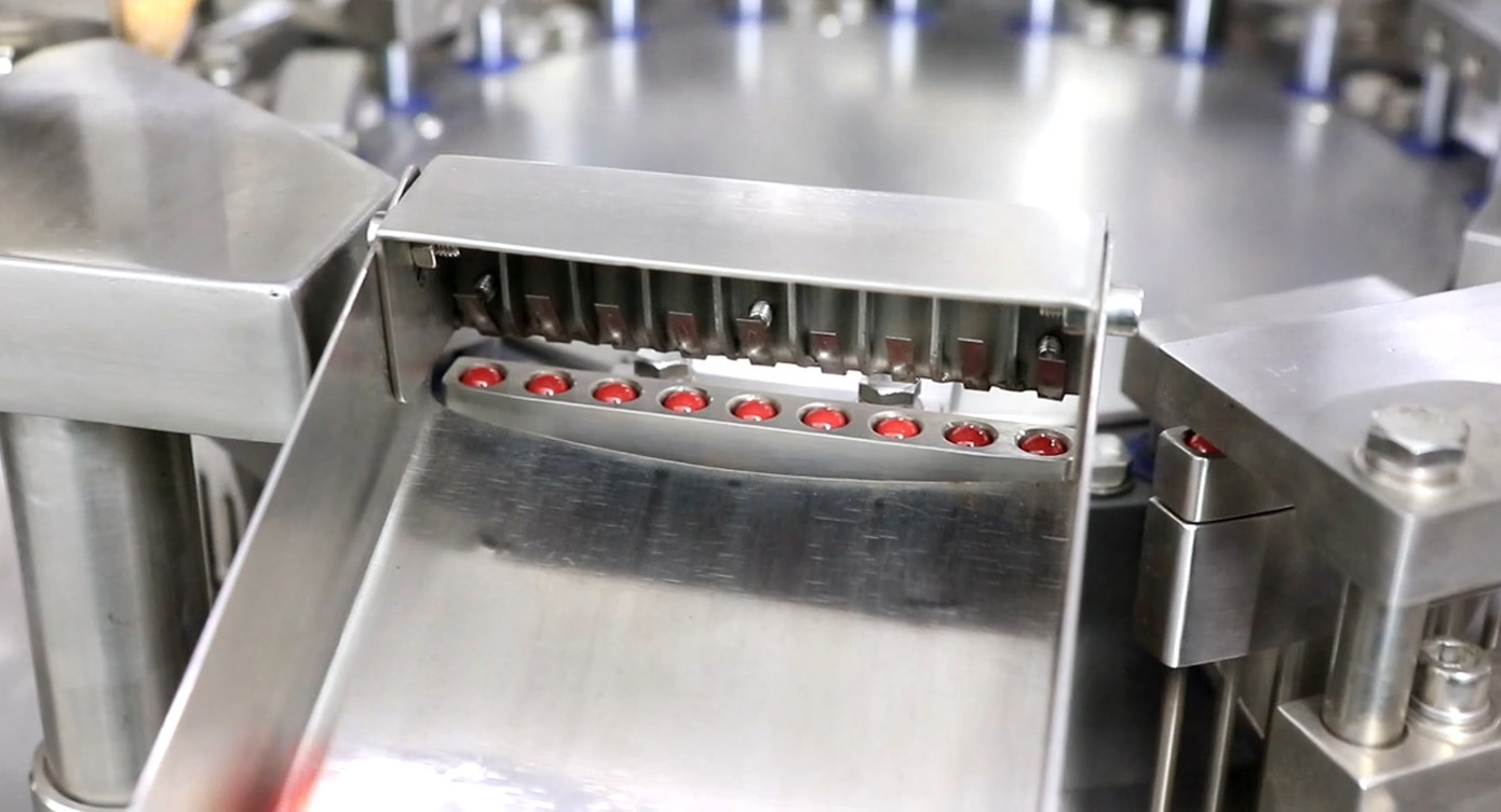 M&aacute;quina de llenado de c&aacute;psulas de cierre y descarga.